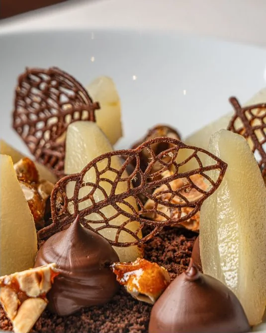 Pere, cioccolato, croccante e foglie di cioccolato traforate.